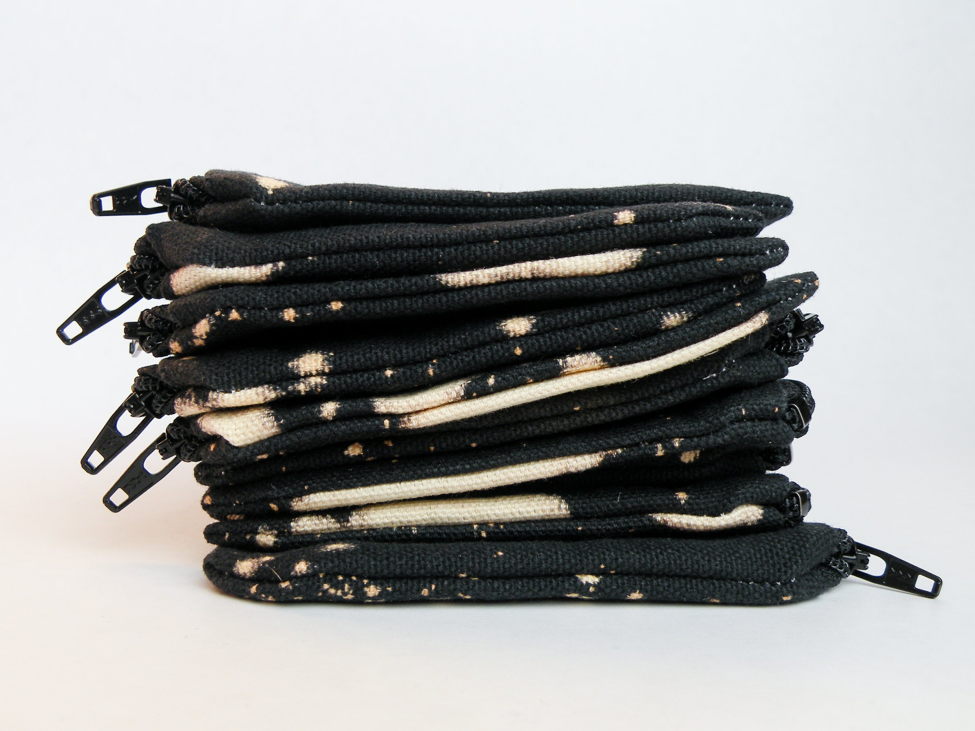Stack of black zipper pouches with bleach dye pattern